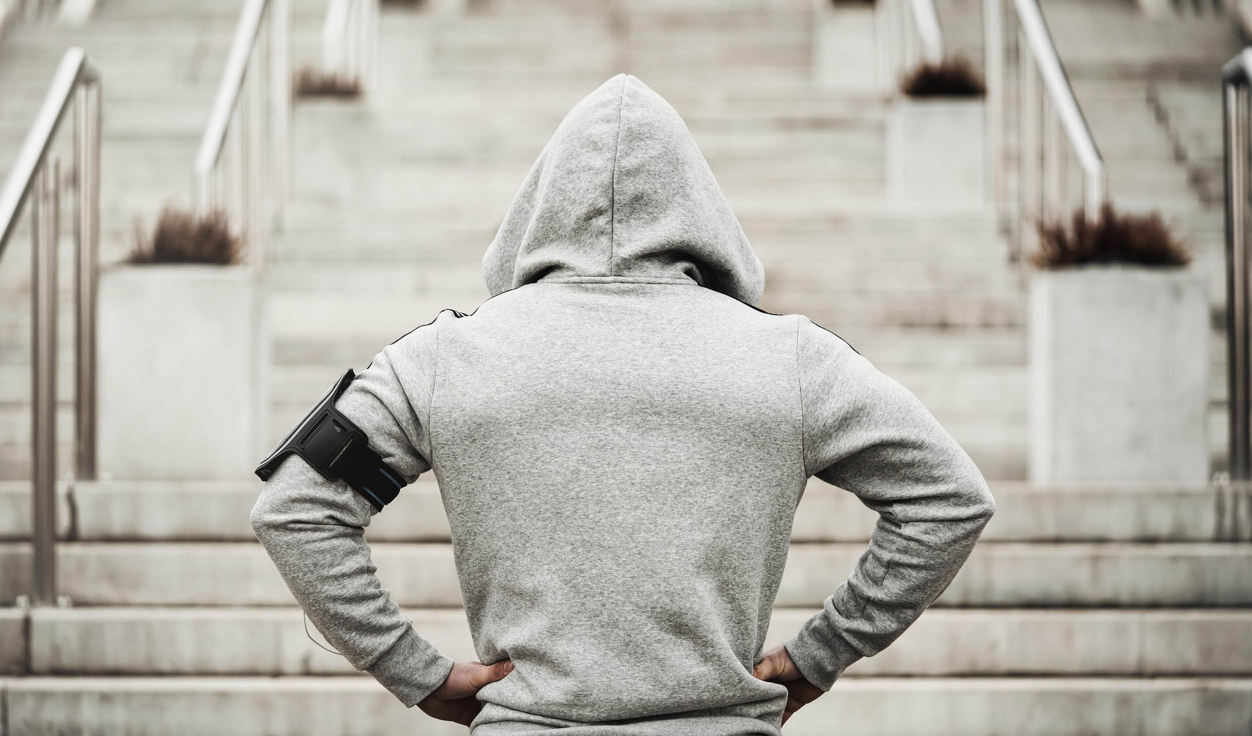 Rear view of hooded sports man about to run upstairs